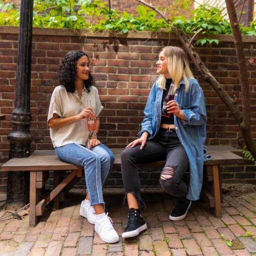 2 women sitting on brown wooden bench