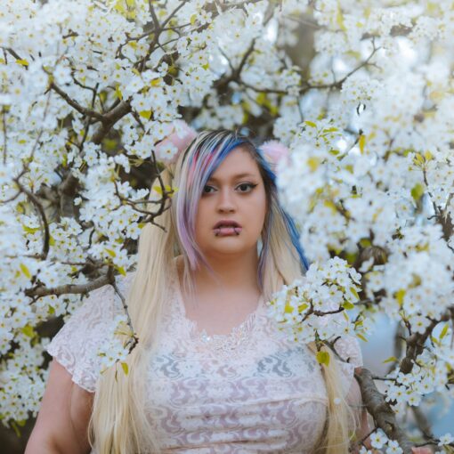 a woman with blue hair standing in front of a tree