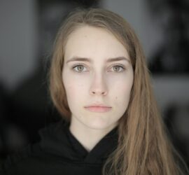 Portrait of a young woman with a serious expression, showcasing natural beauty and depth of emotion.