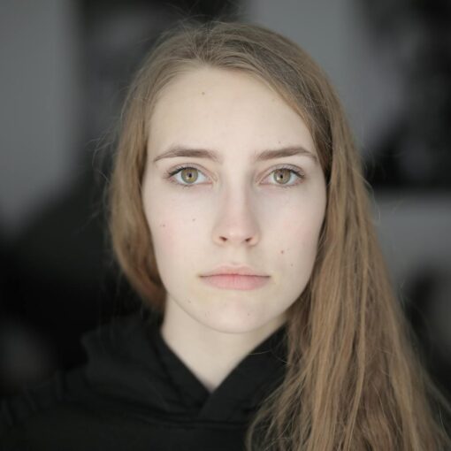 Portrait of a young woman with a serious expression, showcasing natural beauty and depth of emotion.
