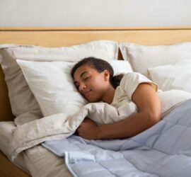 a young girl sleeping in a bed with white sheets