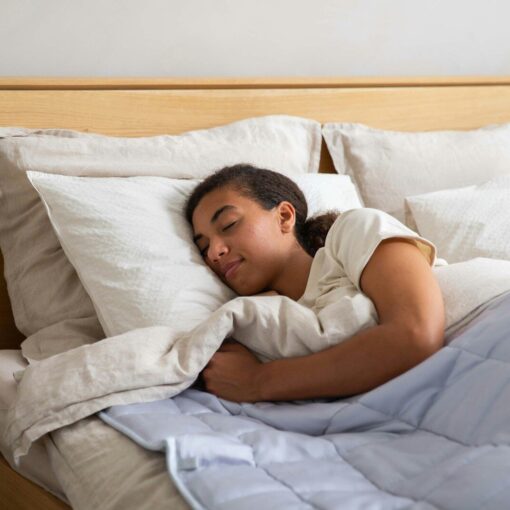 a young girl sleeping in a bed with white sheets